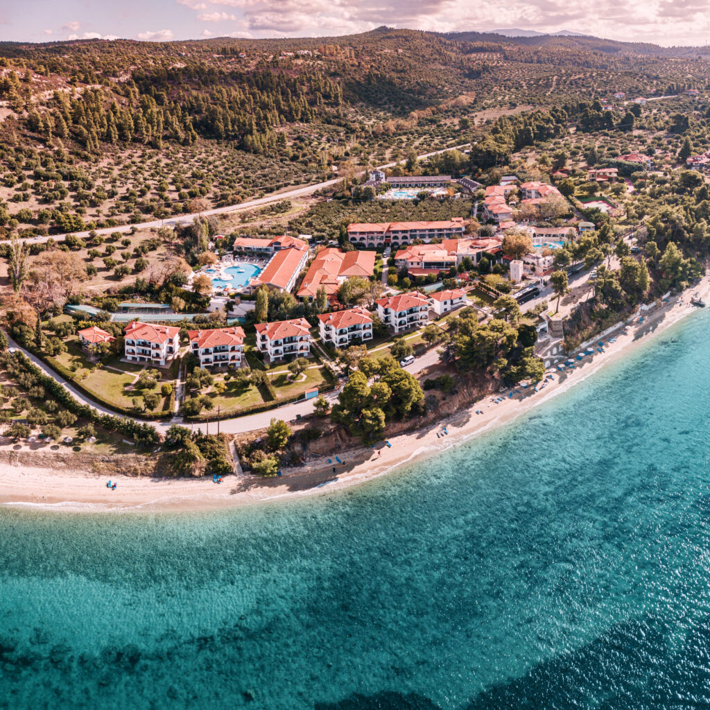 aerial-view-idyllic-sea-shore-sithonia-peninsula-halkidiki-high-roofs-resort-village-with-villas-hotels-with-swimming-pools